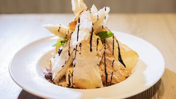 A dessert on a white plate with chocolate drizzle and mint leaves.