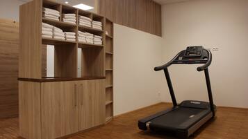 Ein Zimmer mit Laufband, Holzschränken und Regalen mit gefalteten Handtüchern.