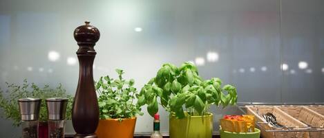 Una encimera de cocina con diversos objetos, entre ellos molinillos de pimienta, una botella de salsa y plantas en macetas.