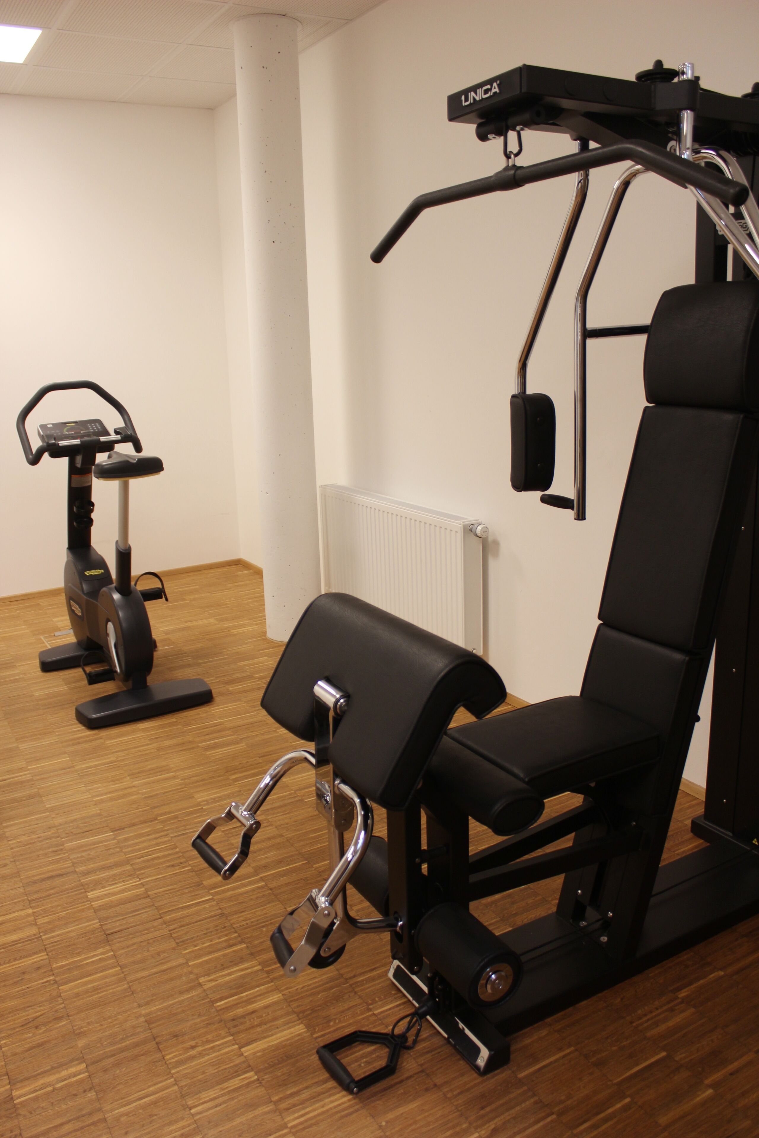 Un gimnasio con equipo de ejercicio, incluyendo una bicicleta estática y una máquina de pesas.