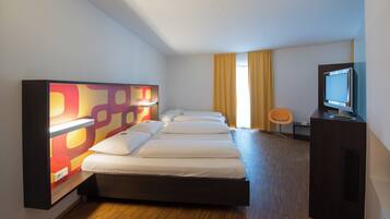 A hotel room with a bed, a TV, and a desk.