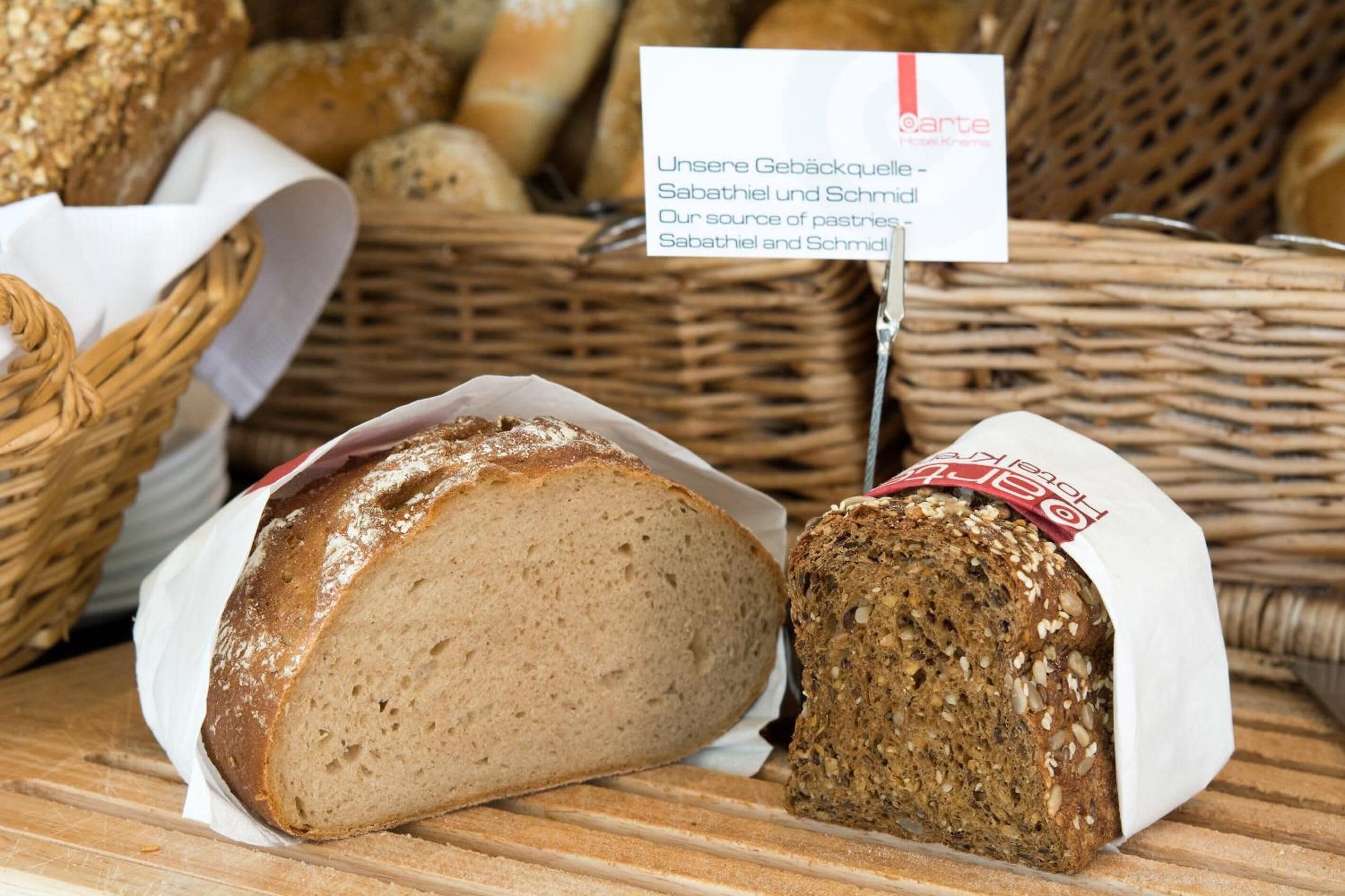 A display of various breads in baskets, including a loaf with a white label.