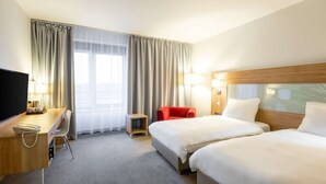 A hotel room with two beds, a desk with a telephone, a red chair, and a TV. - Quality Hotel Ostrava City (Ostrava)