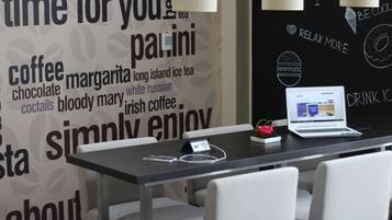 A modern cafe interior with a laptop on a table, a smartphone, and a flower.