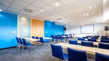 A conference room with blue walls, a white ceiling, and a projector screen.