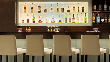 A bar area with multiple liquor bottles on shelves and four bar stools.