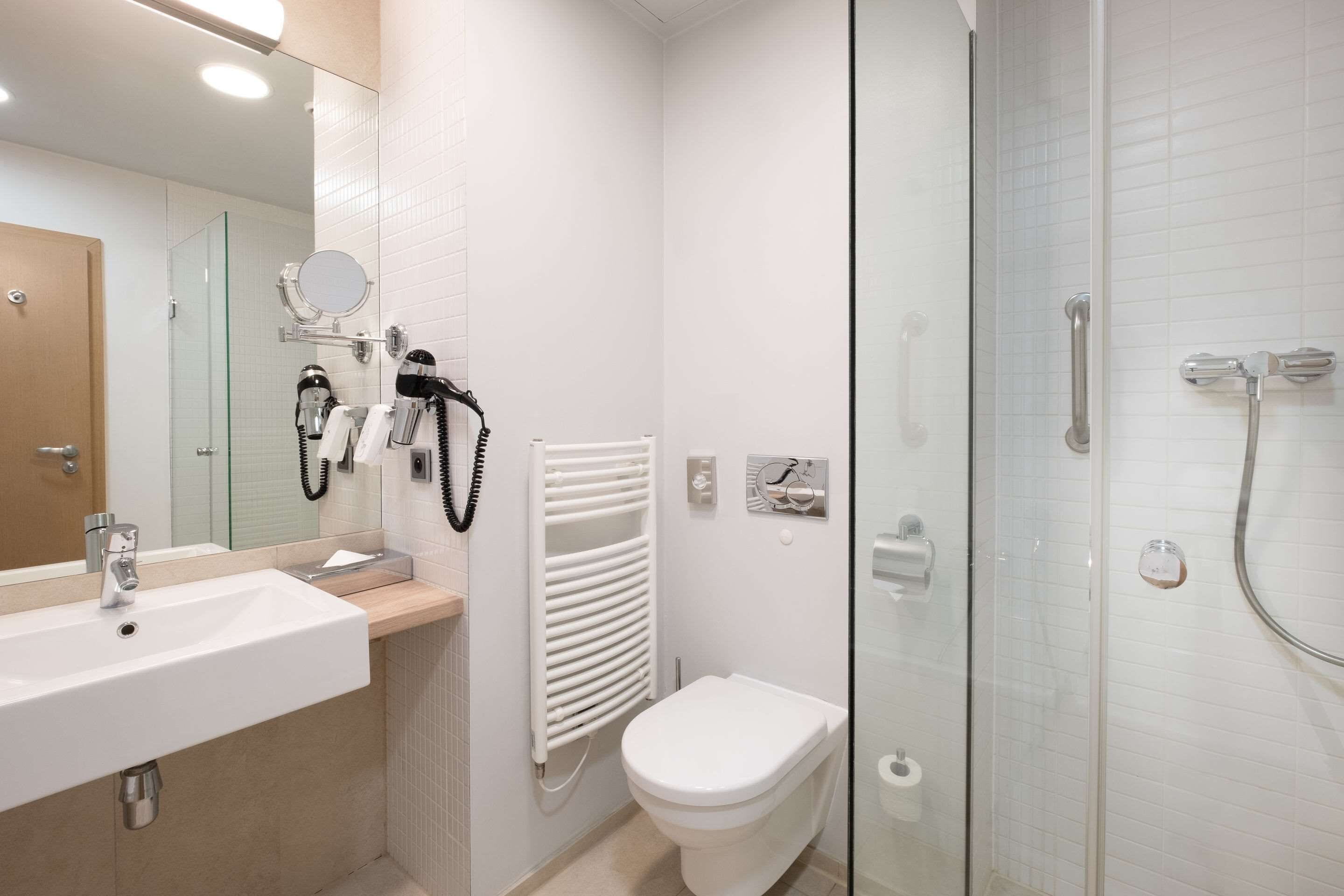 A modern bathroom with a white sink, toilet, and glass shower enclosure.