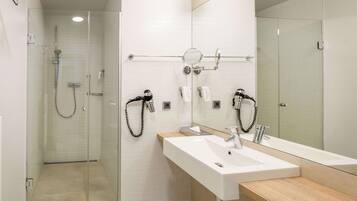 A modern bathroom with a glass-enclosed shower, a large mirror, and a dual sink with a wooden countertop.