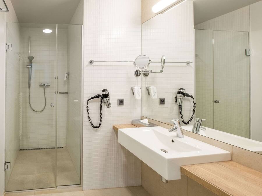 A modern bathroom with a glass-enclosed shower, a large mirror, and a dual sink with a wooden countertop.