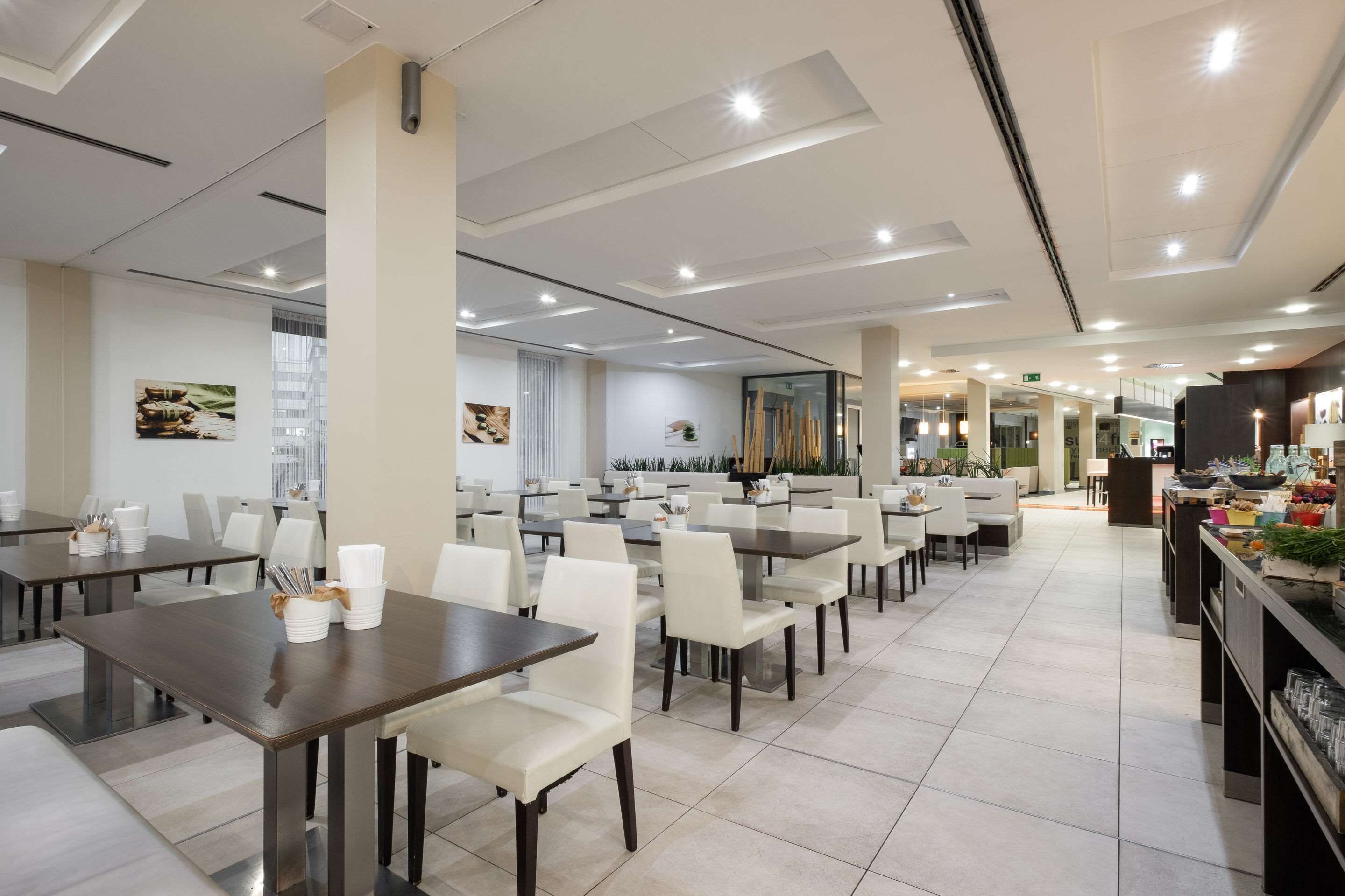 A spacious dining area with multiple tables and chairs, a central serving station, and a view of the adjacent room.