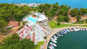 Luchtbeeld van een kusthotel met een zwembad, terras en een jachthaven.