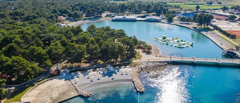 An aerial view of a coastal area with a marina, boats, and a bridge.