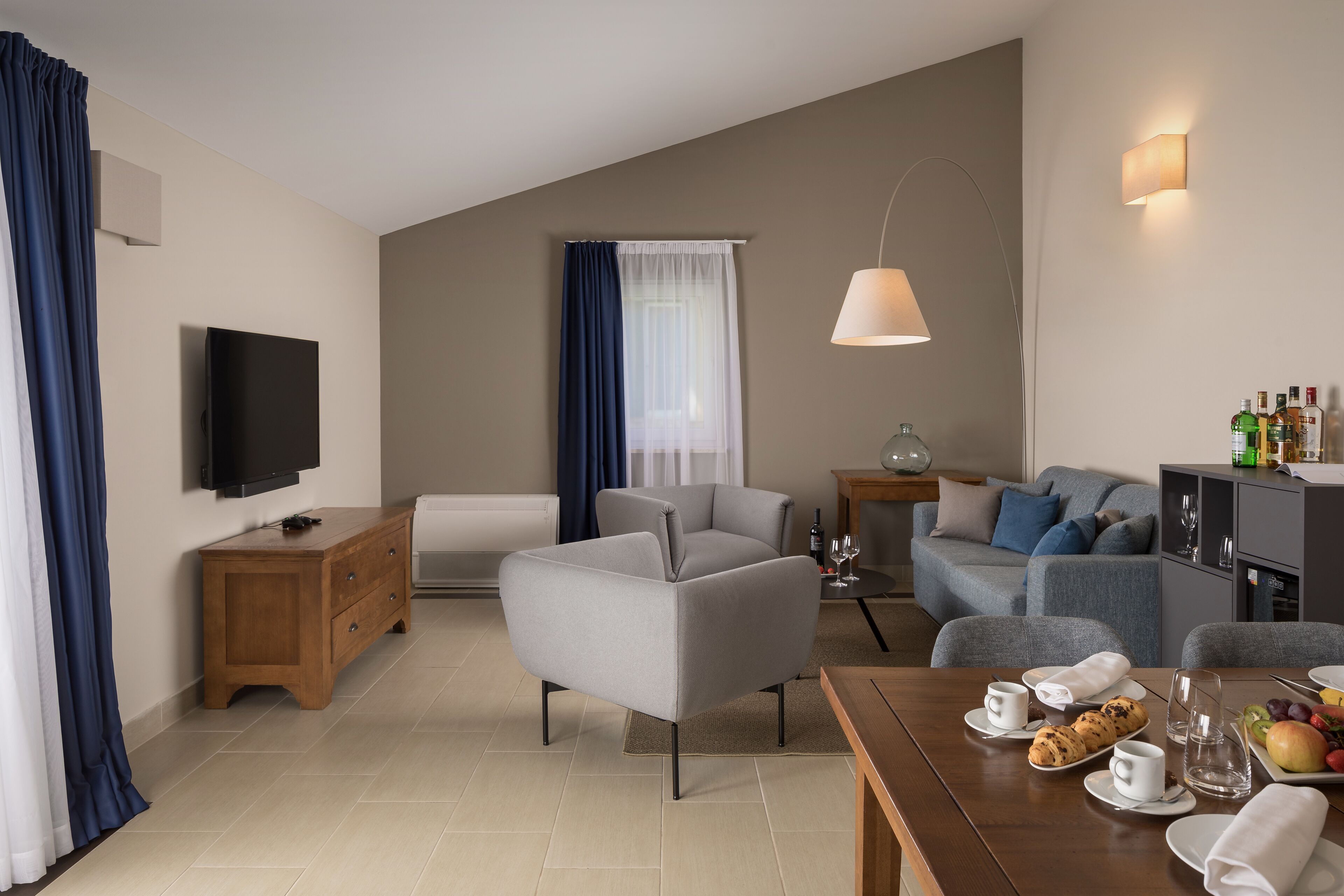 A modern living room with a sofa, a coffee table, and a dining table set with breakfast items.