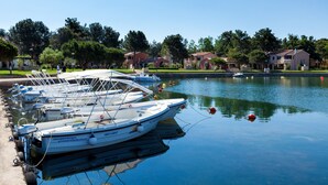 Un port de plaisance où sont amarrés plusieurs bateaux, entouré de bâtiments résidentiels et d’arbres.