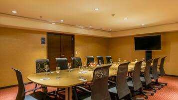 A conference room with a long table, chairs, and a flat-screen TV on the wall.