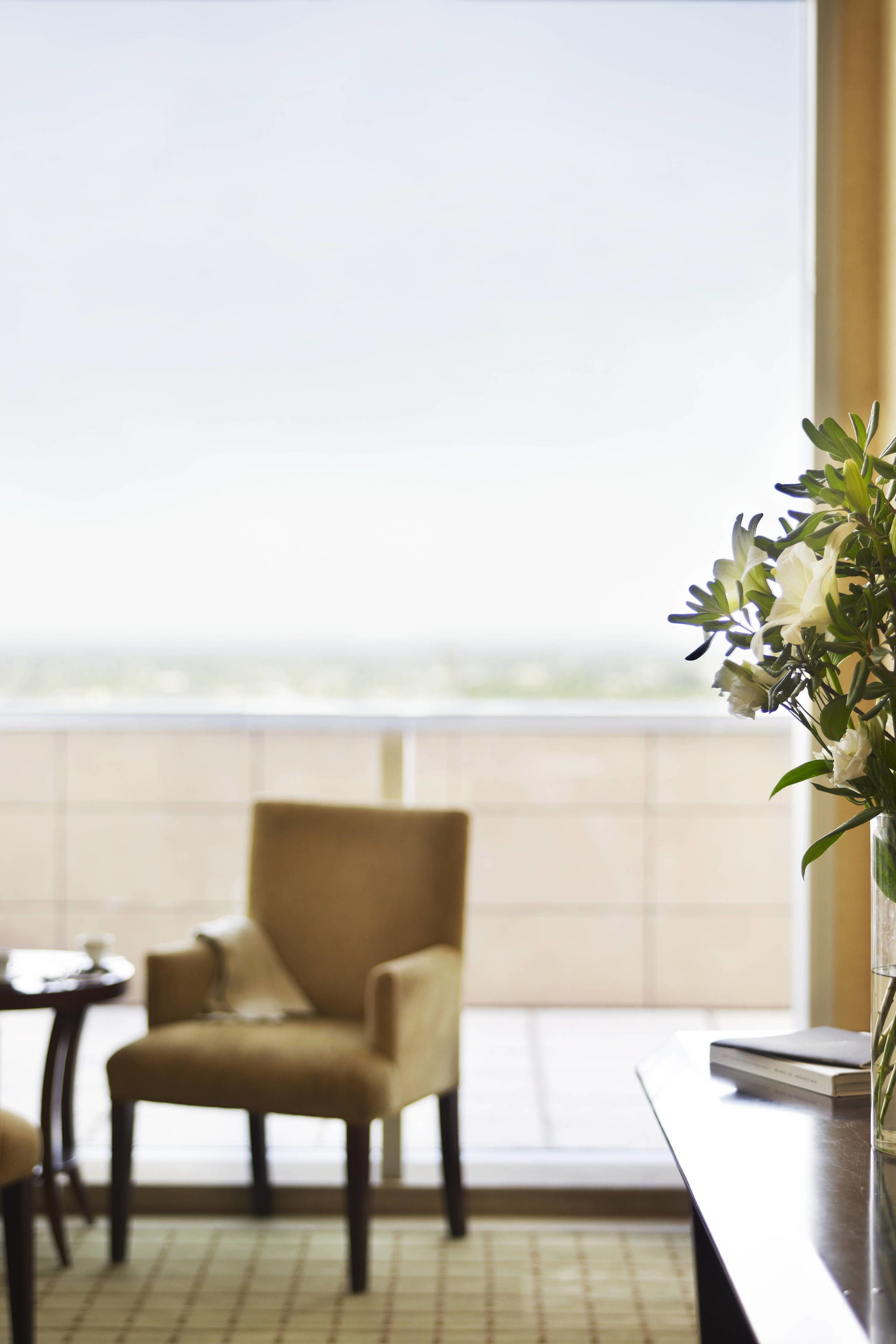 A room with a chair and a table near a window.