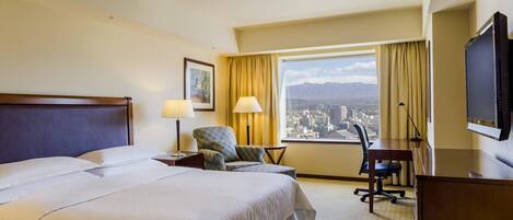 Una habitación de hotel con una cama grande, un escritorio, una silla, un televisor y una ventana con vistas a la ciudad.
