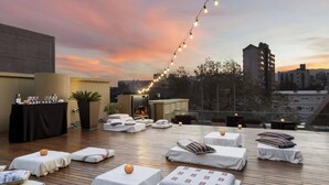 Un salón en la azotea con mesas al aire libre, una zona de bar y una chimenea.