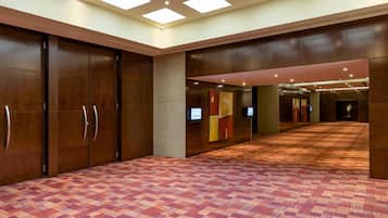 A spacious hallway with a patterned carpet, wooden paneling, and recessed lighting.