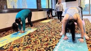 A room with large windows, a patterned carpet, and people doing yoga on mats. - Hotel Quinta Mision (Bocoyna)
