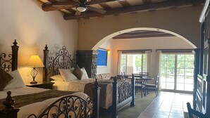 A bedroom with two beds, a sitting area with a table and chairs, and a view of the outdoors. - Hotel Quinta Mision (Bocoyna)