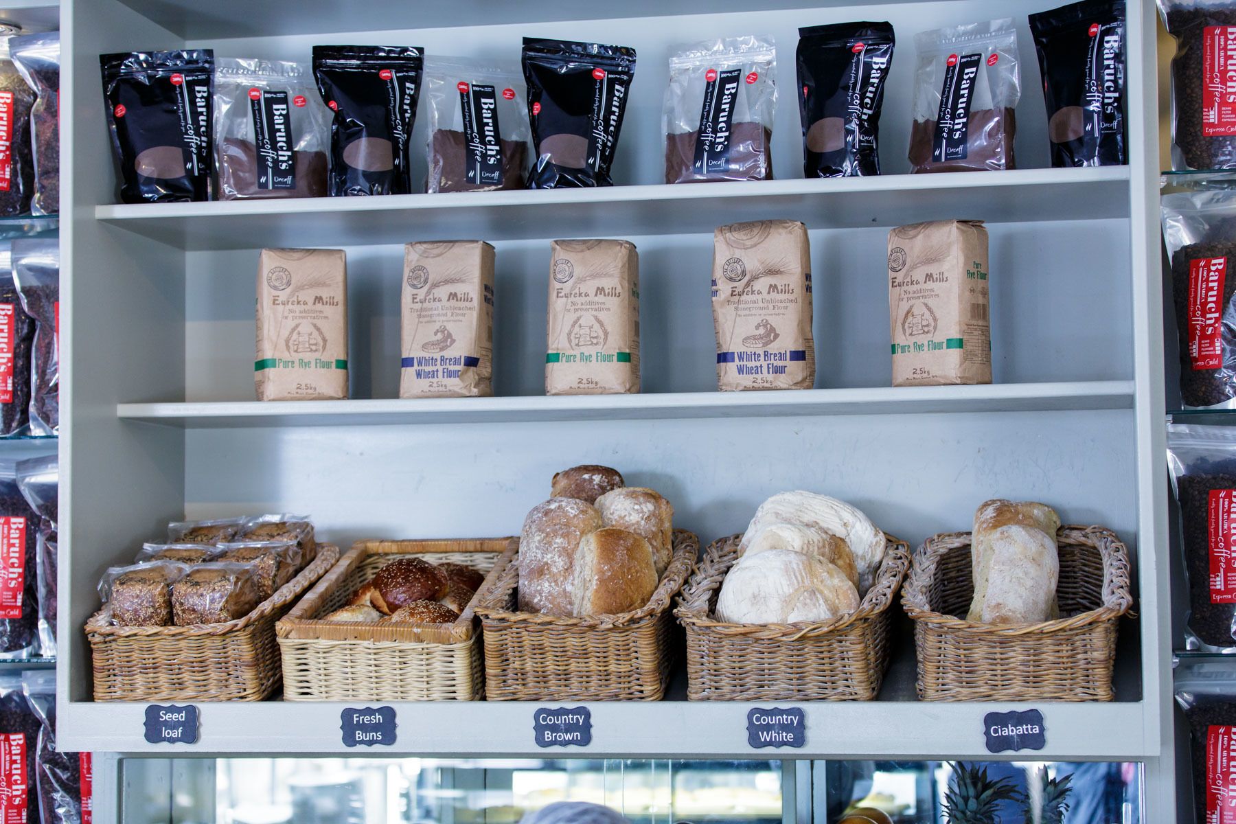 Shelves stocked with coffee, flour, and various types of bread.