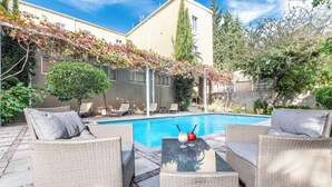 Zona junto a la piscina con mobiliario de mimbre y vistas despejadas al agua.