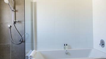 A bathroom with a bathtub, a shower, and a glass-enclosed shower area.