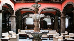 Un hall con una fuente central, varias zonas de estar y puertas abovedadas.