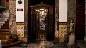 Una entrada imponente con una reja de hierro forjado, una escalera y un muro de azulejos con un letrero que dice "PLANTA BAJA".