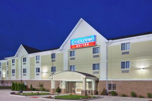 Ein Hotel mit einem gut sichtbaren 'CANDLEWOOD SUITES'-Schild, mehreren Fenstern und einem gut beleuchteten Eingang.