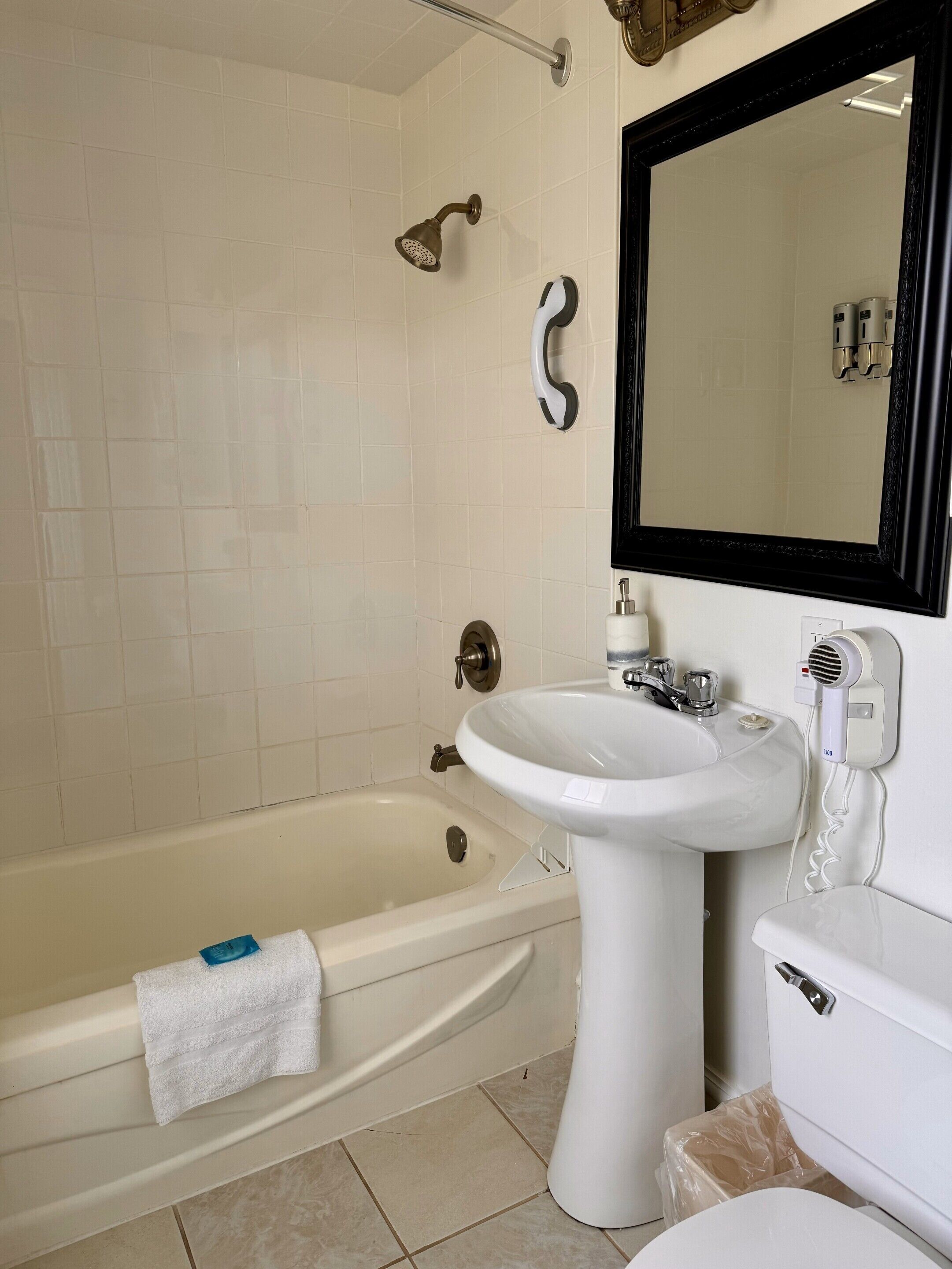 Ein Badezimmer mit einer Badewanne, einem Waschbecken, einem Spiegel und einem Handtuch.