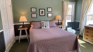 A bedroom with a bed, two bedside tables with lamps, a dresser, a chair, and a window with curtains.