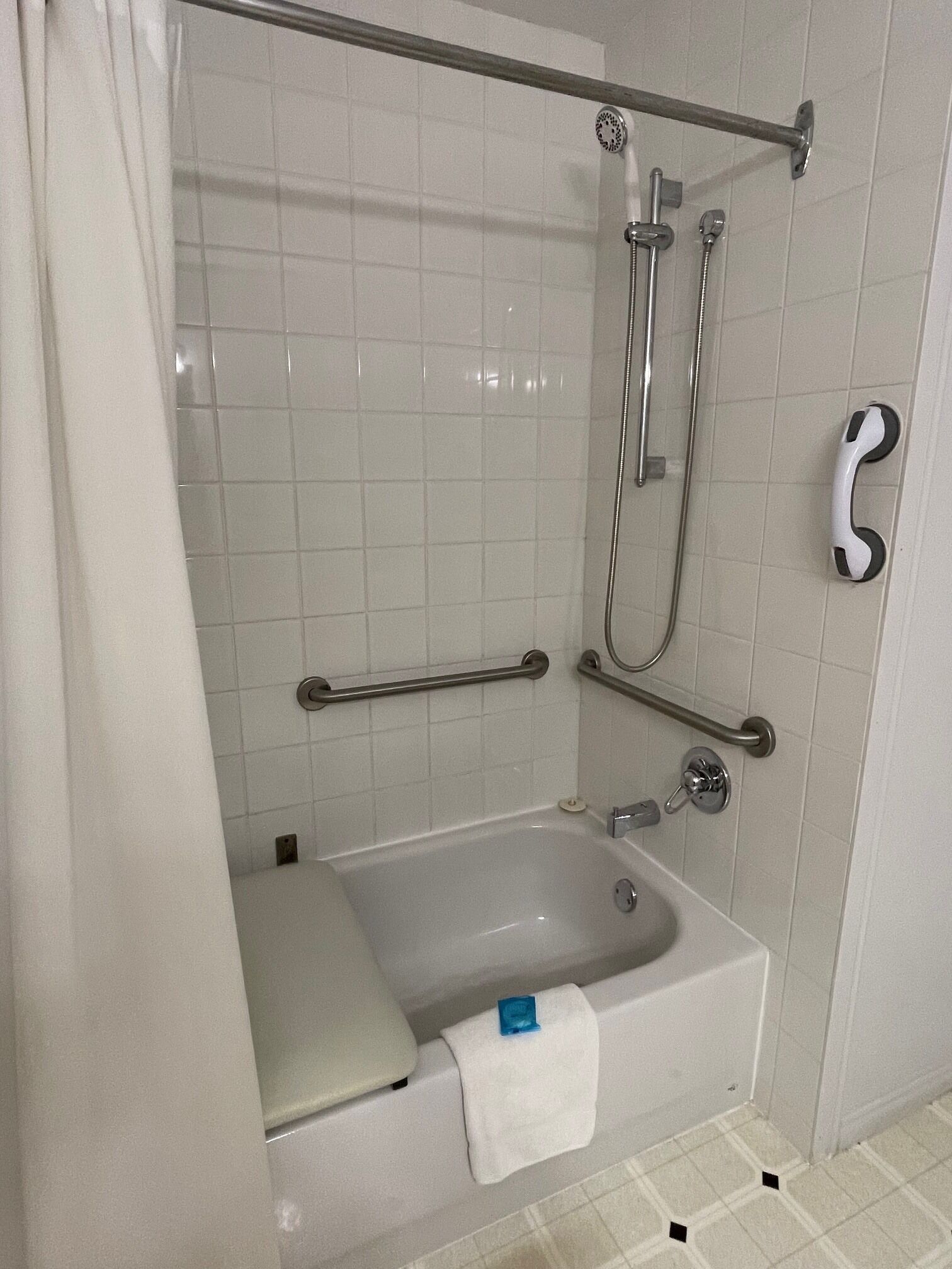 A bathroom with a bathtub, a shower, grab bars, and a towel rack.