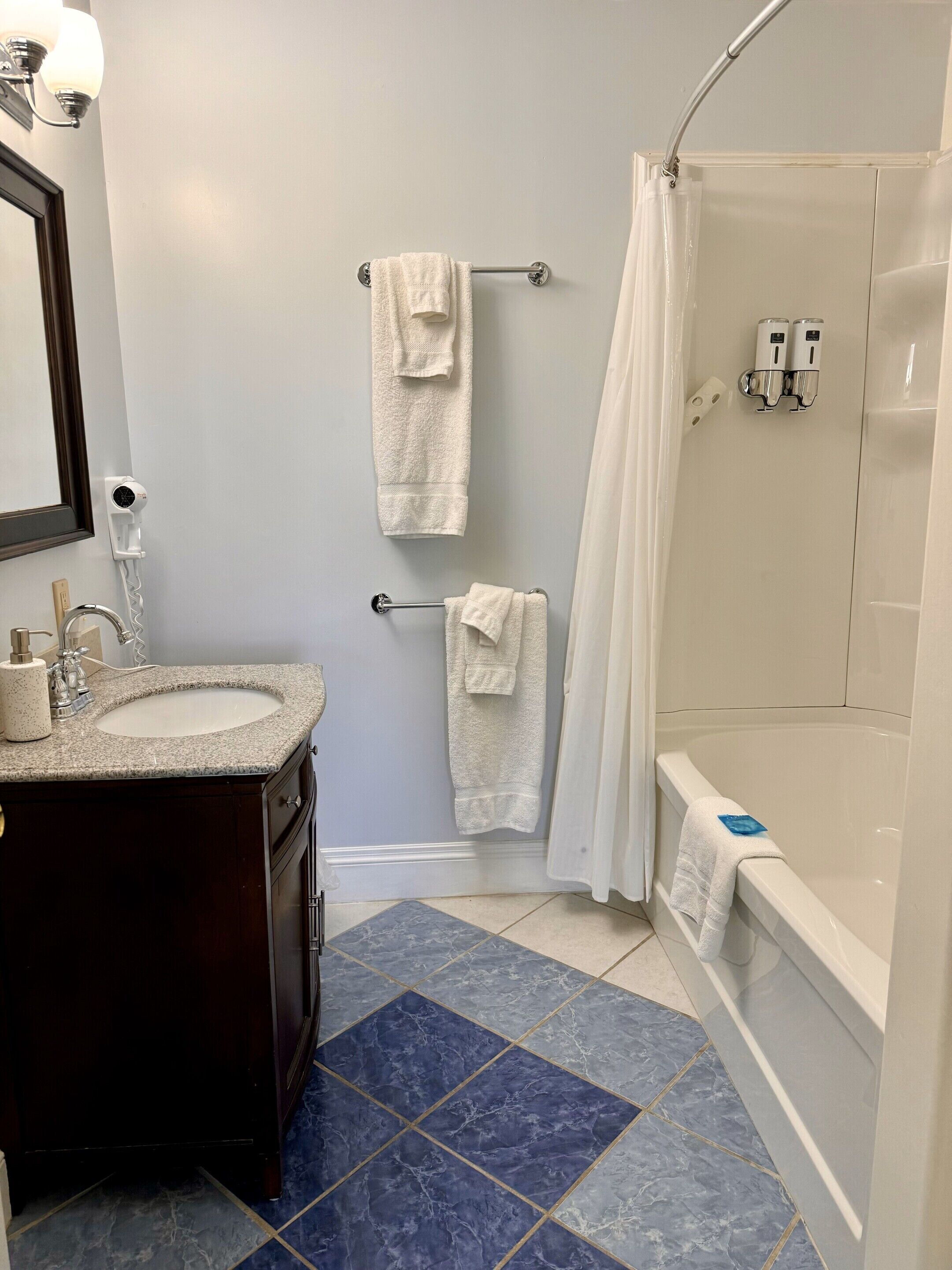 A bathroom with a sink, mirror, towel rack, shower curtain, and a bathtub.