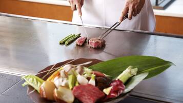 Un cocinero preparando comida en una plancha con diversos tipos de carne y verduras.