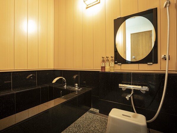 A modern bathroom with a black marble sink, a large mirror, and a handheld showerhead. - Hotel Agora Osaka Moriguchi (Moriguchi)