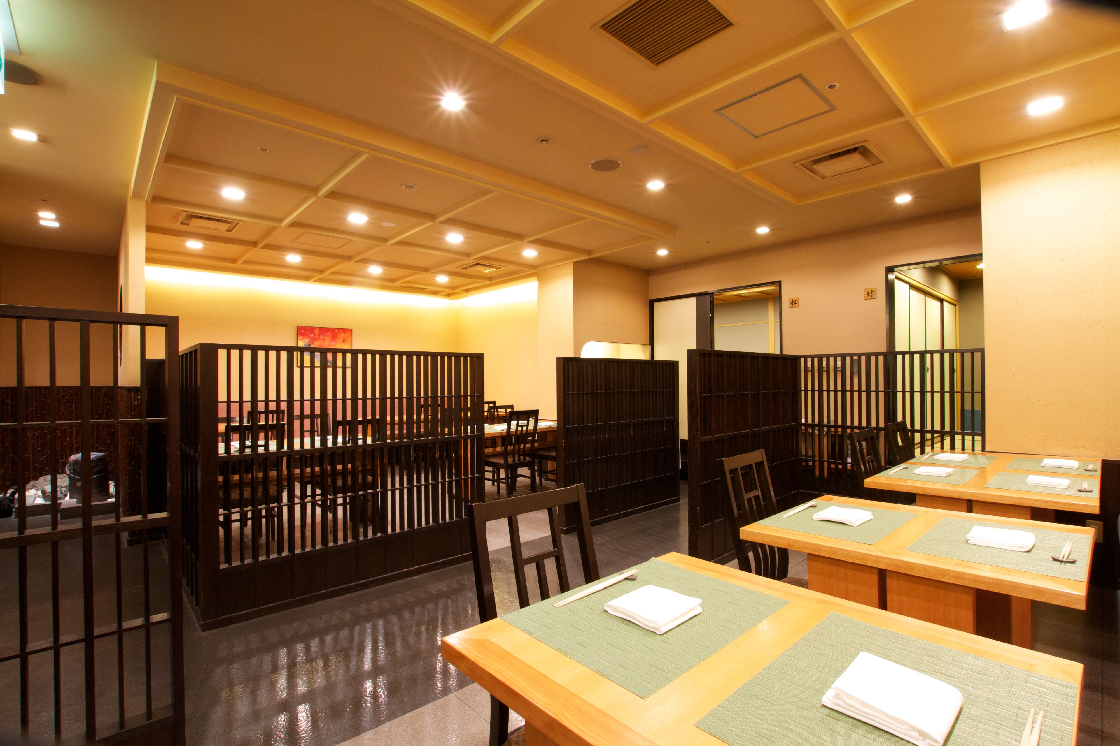 A restaurant with wooden tables and chairs, partitioned booths, and a warm interior.