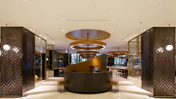 Un moderno vestíbulo de hotel con un mostrador de recepción central, ventanas amplias y un diseño de pared con patrón de espiga.