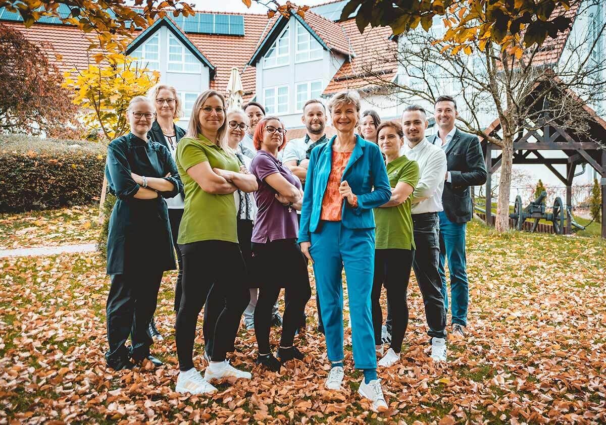Un gruppo di persone in piedi all'aperto, con un edificio sullo sfondo.