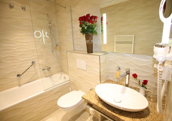 A modern bathroom with a glass shower enclosure, a white toilet, and a granite countertop with a sink and mirror. - Hotel Marschall Duroc (Markersdorf)