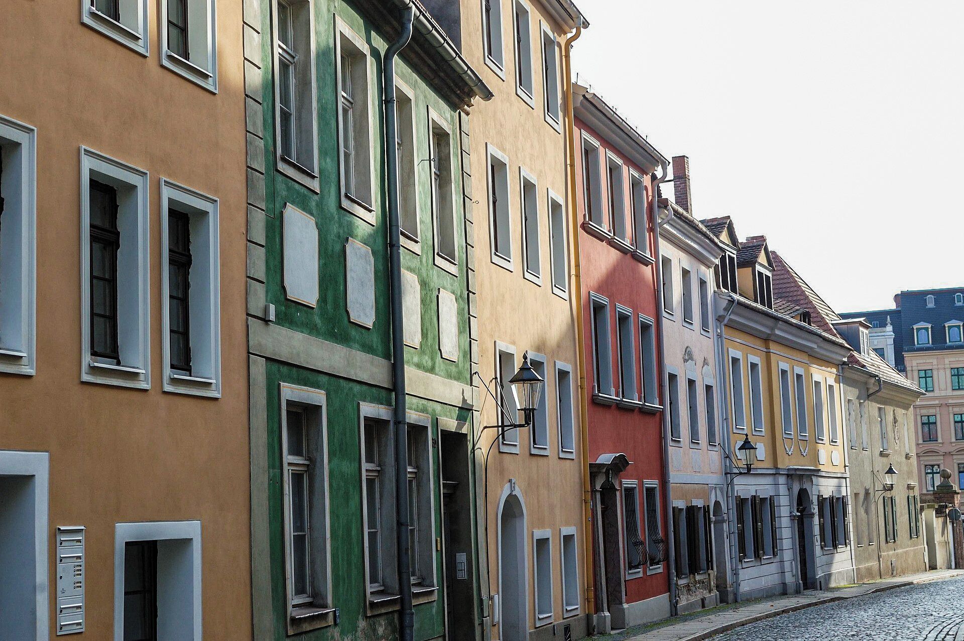 Una hilera de edificios coloridos con diseños de ventanas uniformes y una calle adoquinada.