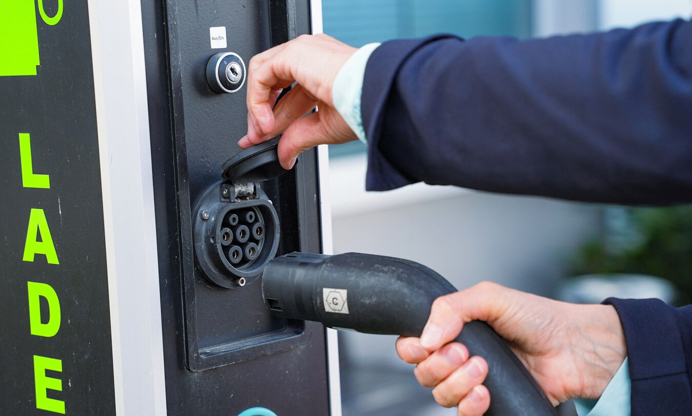 Una persona conectando un vehículo eléctrico a una estación de carga.