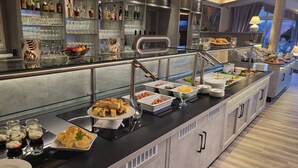 A buffet area with various food options, a bar with liquor bottles, and a view of the outside through large windows.