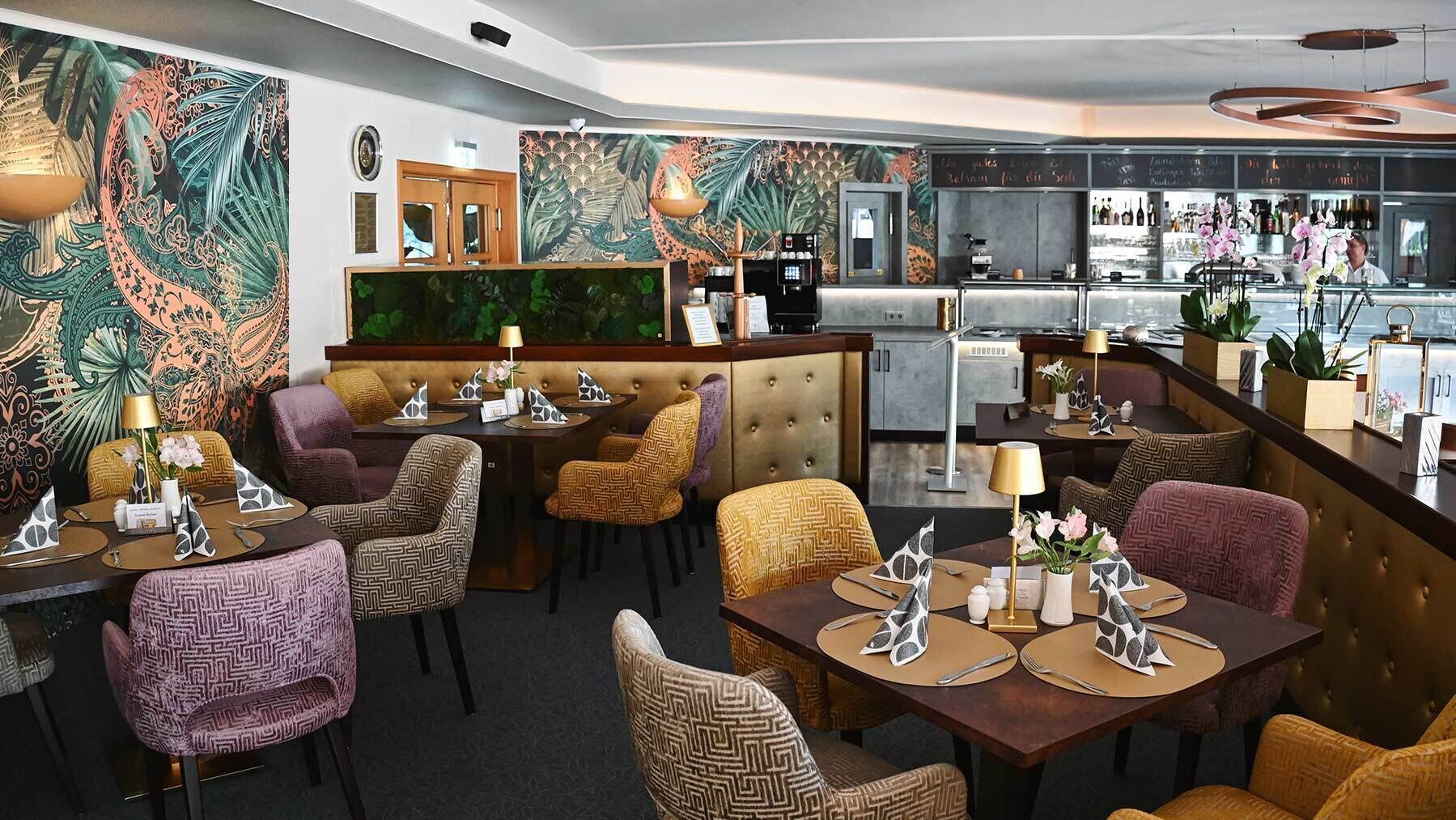 Restaurante com área de bar, paredes estampadas e diversas opções de assentos, incluindo cabines e mesas.