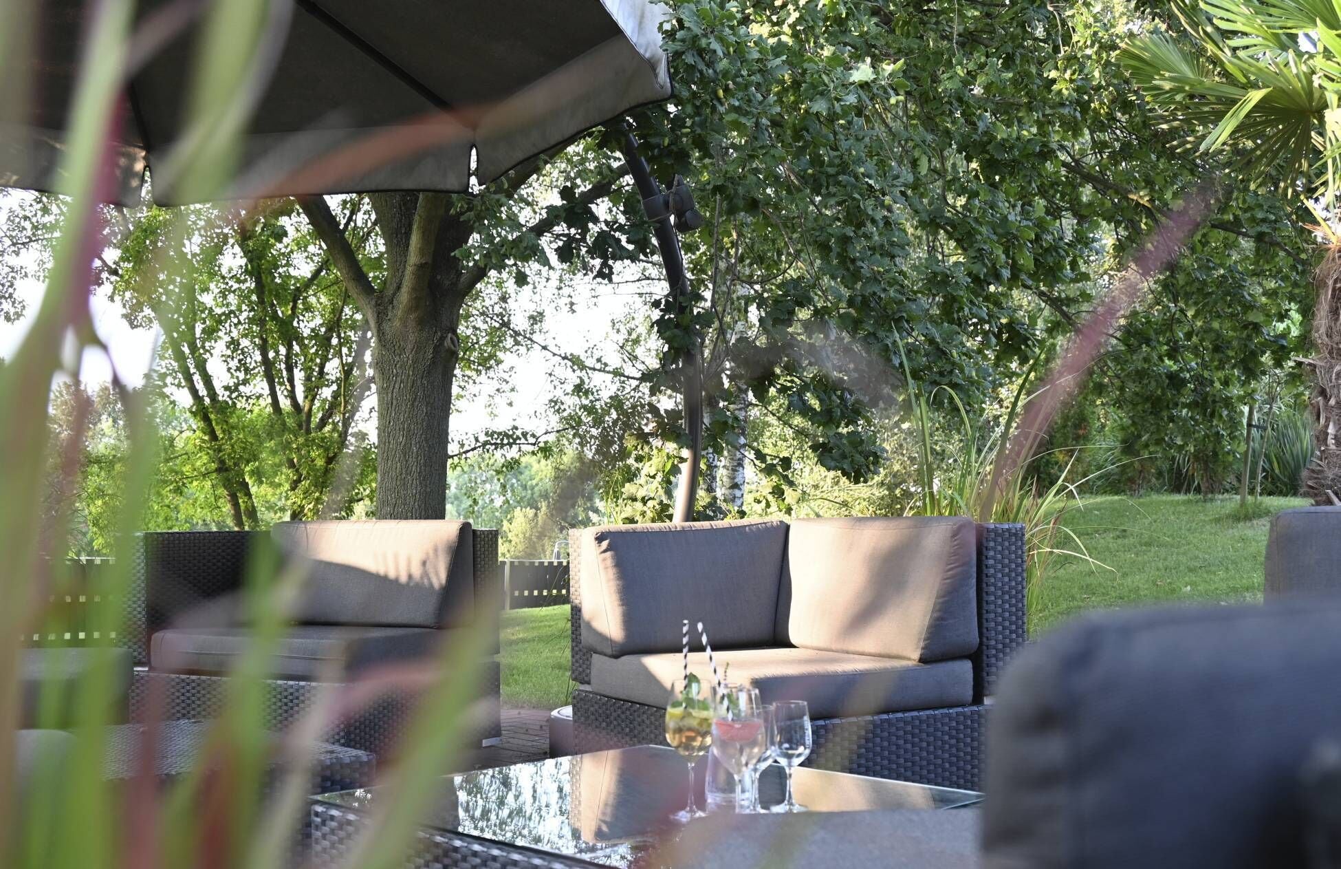 Een terras met een tafel, stoelen en een zonnescherm.