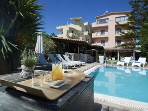 Alberca al aire libre, sombrillas en la alberca y camastros