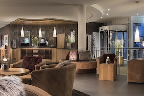 A modern lobby with leather seating, a reception desk, and a glass elevator. - Best Western Plus Hotel Willingen (Willingen)