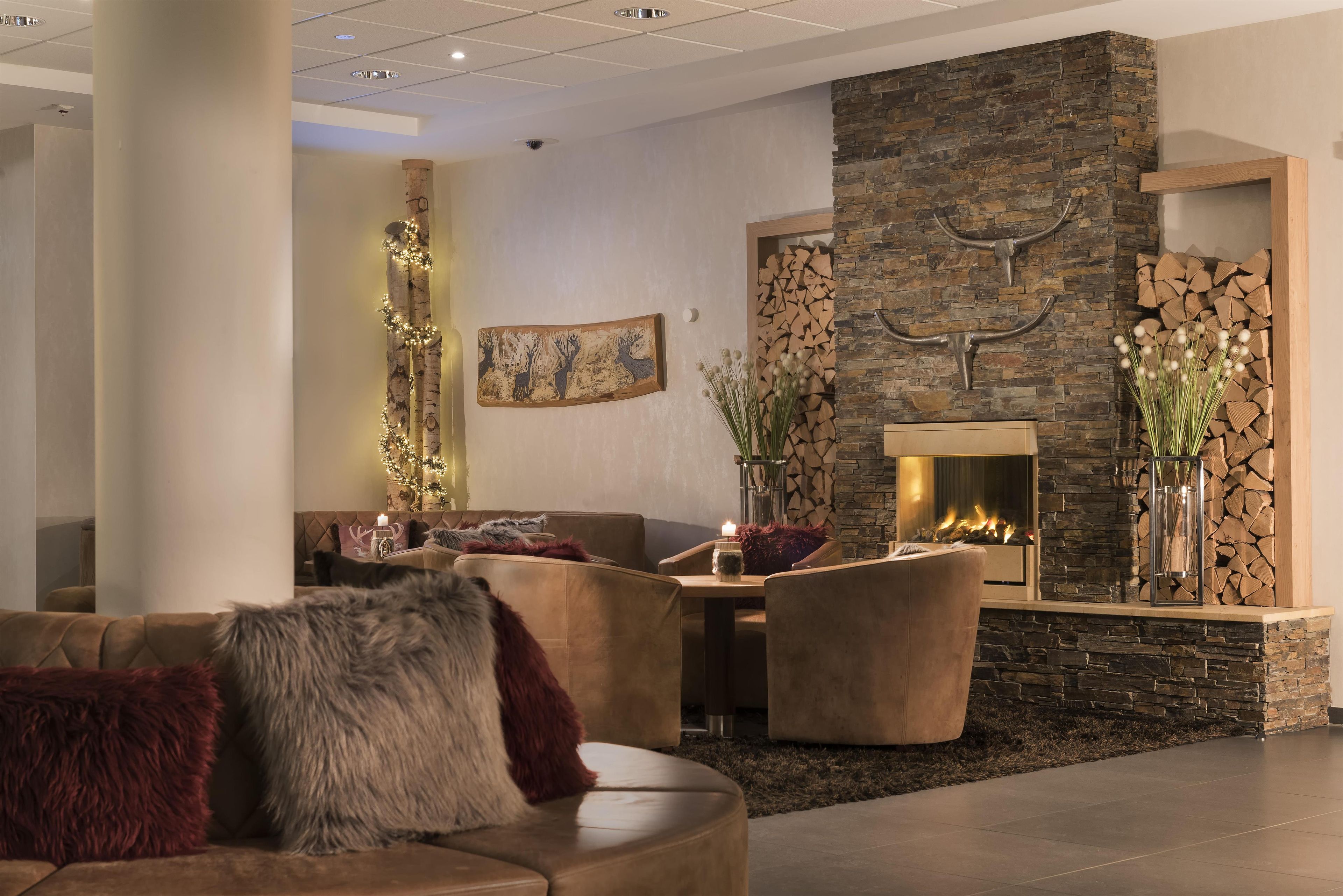 Ein modernes Wohnzimmer mit Kamin aus Stein, Ledermöbeln und dekorativen Elementen wie einem Gemälde und einer Wandskulptur.