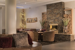 A modern living room with a stone fireplace, leather furniture, and decorative elements like a painting and a wall-mounted sculpture. - Best Western Plus Hotel Willingen (Willingen)